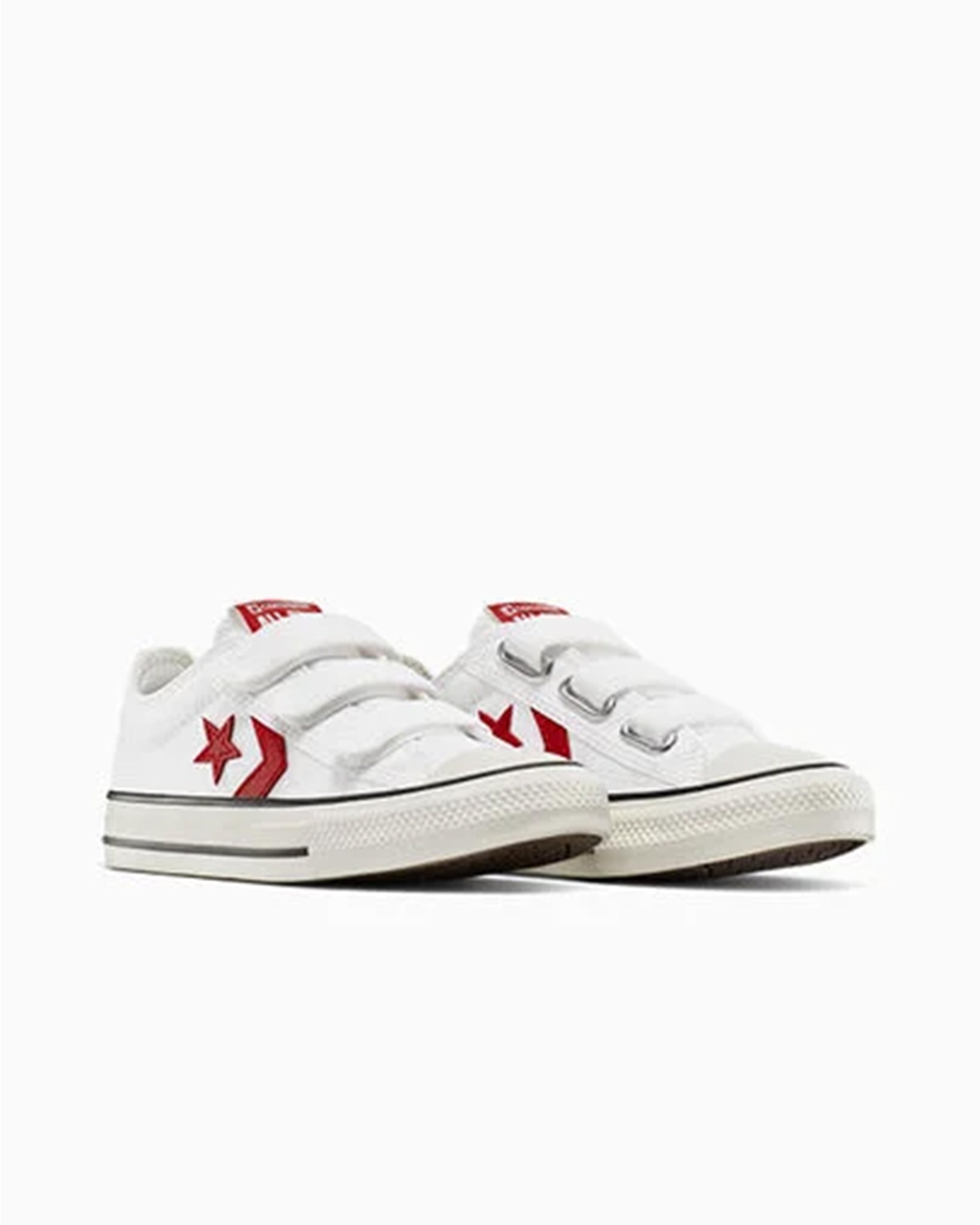 Pair of white Converse sneakers with red logos and velcro straps, angled front view.
