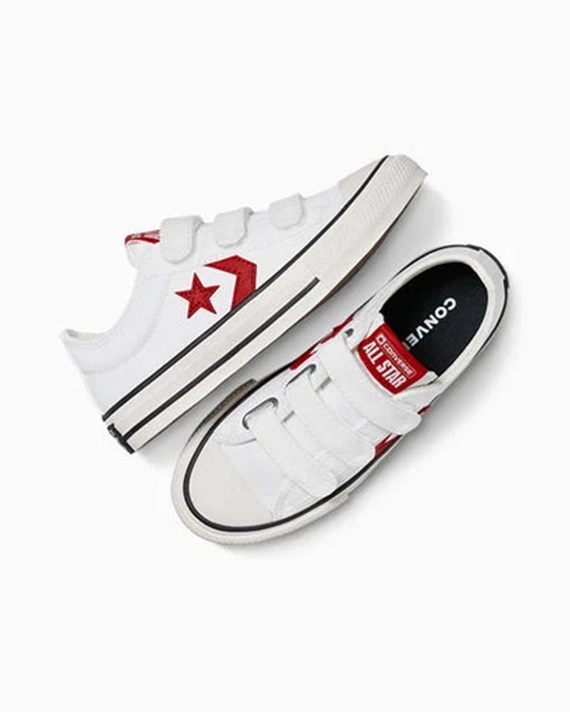 Overhead view of white Converse sneakers with velcro straps, one shoe upright, the other side-lying.