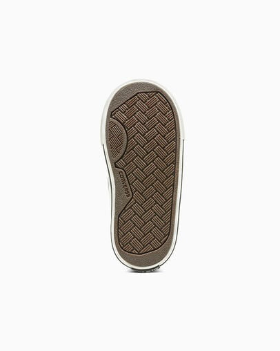 White Converse sneaker with brown rubber sole, bottom view.