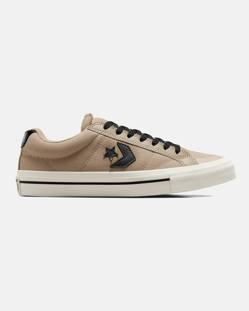 Side view of beige low-top Converse sneakers with black laces, black star logo, and white rubber sole with a black stripe.