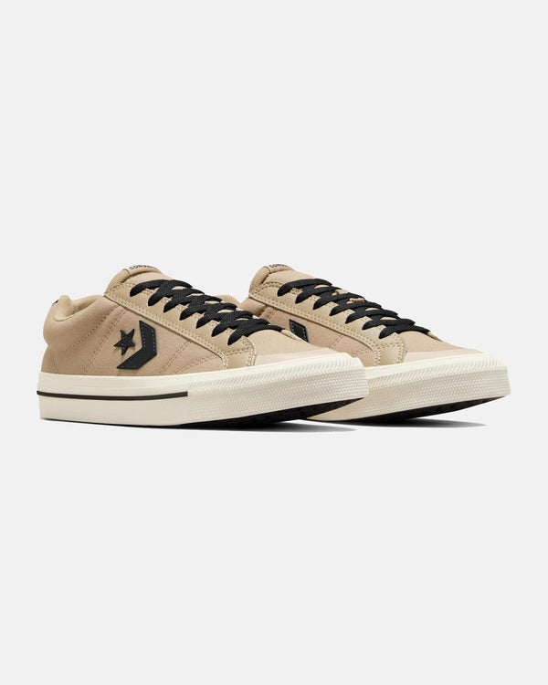 Pair of beige low-top Converse sneakers with black laces, black star logo, and white rubber sole with a black stripe.