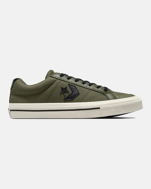 A side view of an olive green low-top sneaker featuring black laces, a black star logo, and a white rubber sole with a black stripe.