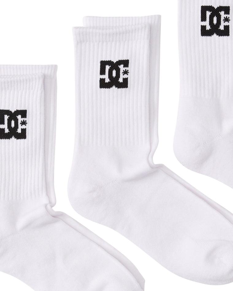 Angled flat lay of three white DC crew socks showing the black logo and ribbed detail.