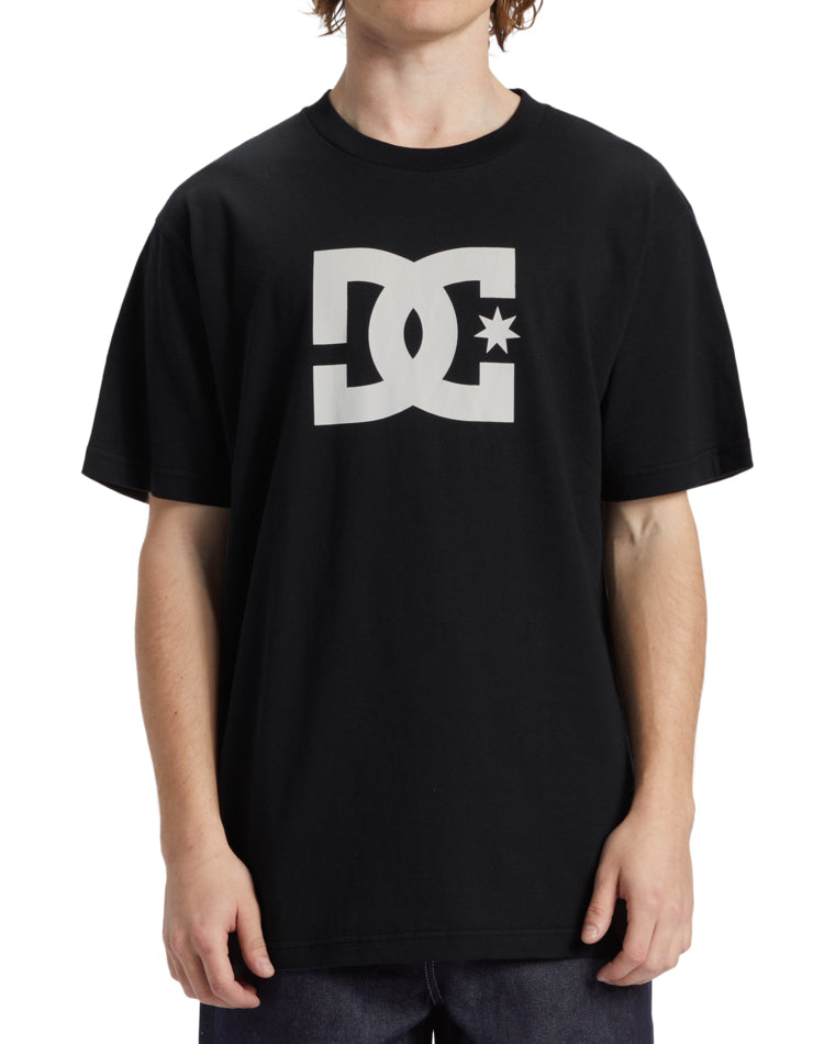 Model wearing a black DC t-shirt with oversized white DC Shoes logo printed across the chest.