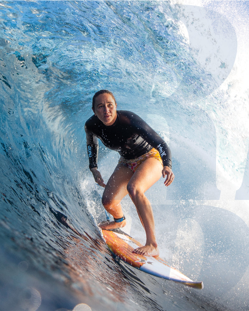 Carissa Moore riding inside a powerful barrel, focused and balanced on a shortboard in perfect conditions.