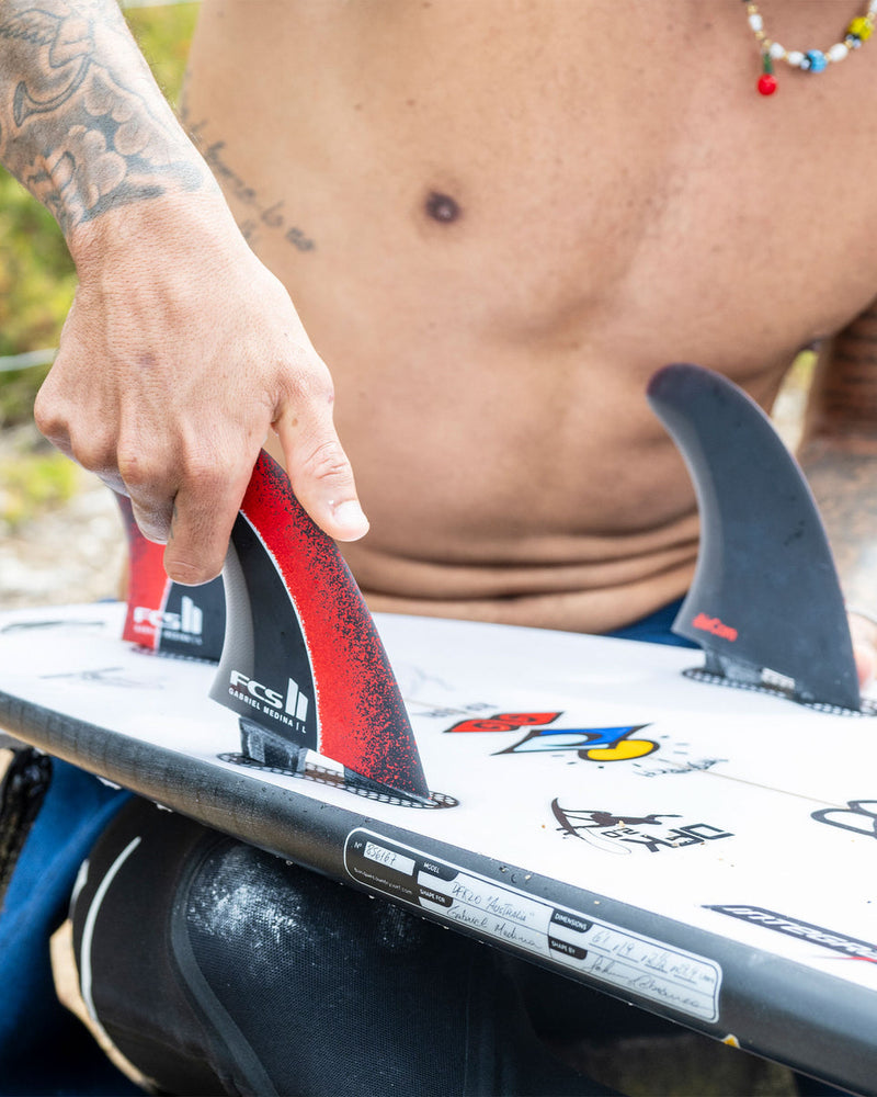 Installing FCS II Gabriel Medina fins onto a white shortboard with custom artwork and decals.