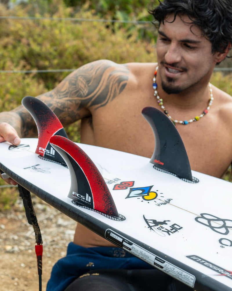 Surfer inspecting FCS II Gabriel Medina fins on a setup board before heading out to surf.