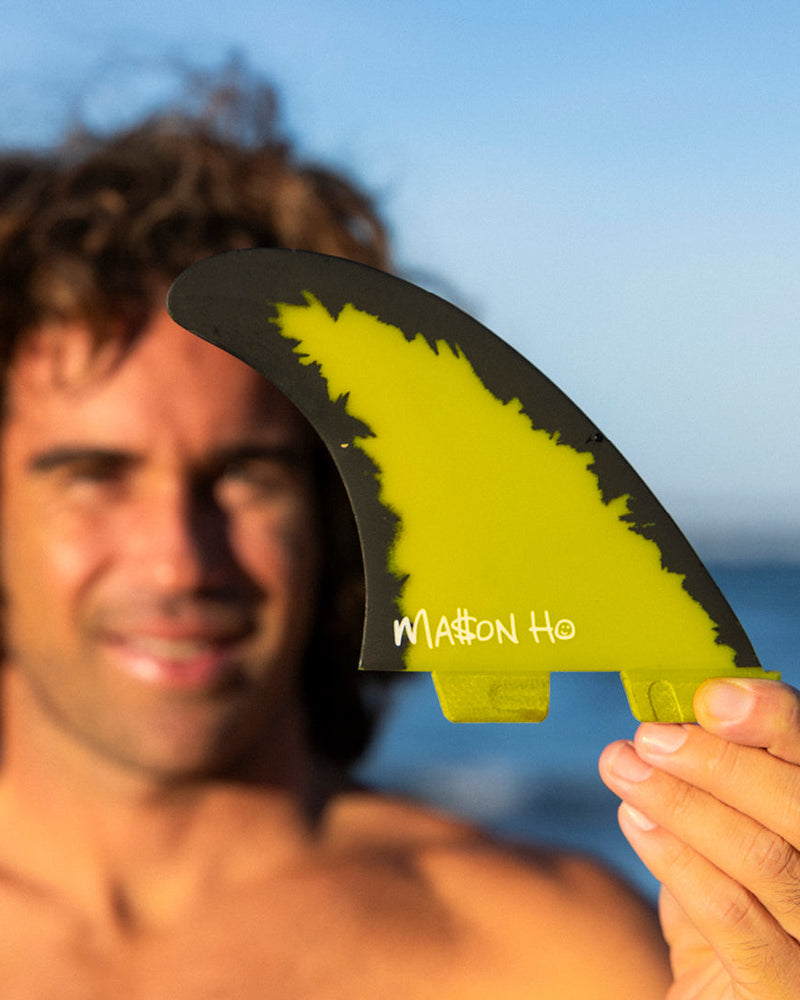 Surfer displaying FCS II Mason Ho fin in natural light, showing its bold colour and unique edge detail.