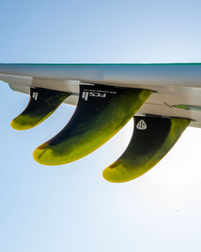 Close-up of FCS II Mark Richards Twin fins fully installed in surfboard, showcasing curved shape and dual-tab base.