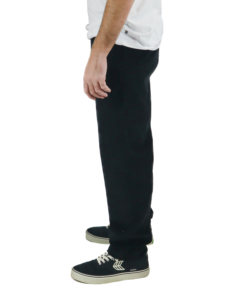 Side view of black corduroy pants paired with Cariuma skate sneakers