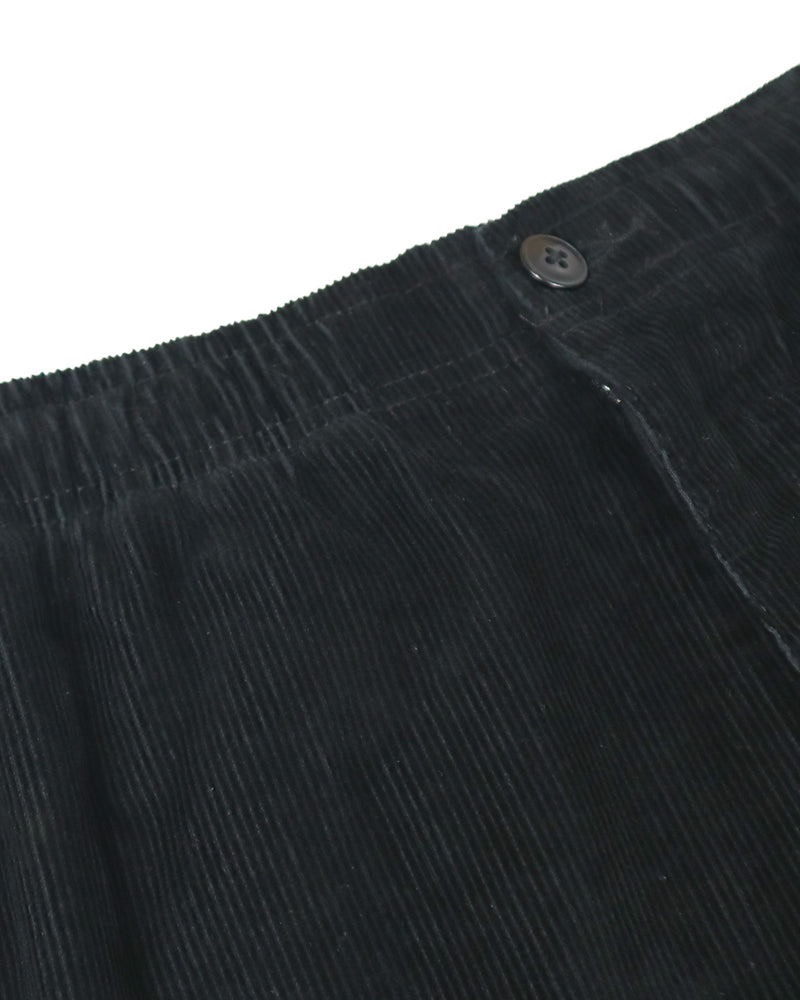 Close-up of black corduroy fabric with elastic waistband and button closure