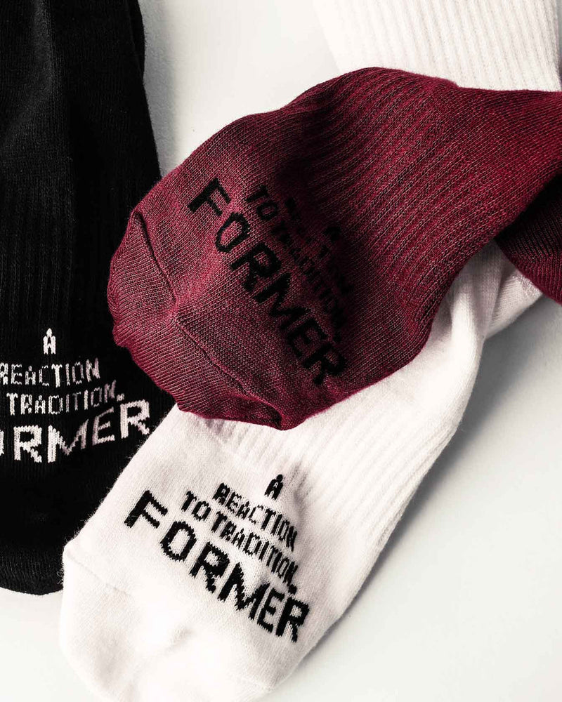 Close-up of Former socks showing textured knit and "A Reaction to Tradition" text on sole.