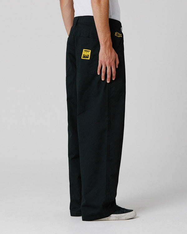 Rear view of black pants featuring yellow logo patch on pocket