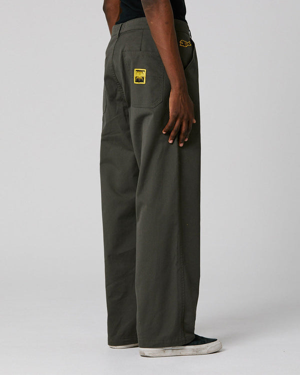 Rear view of dark olive pants featuring yellow patch detail and relaxed wide-leg fit