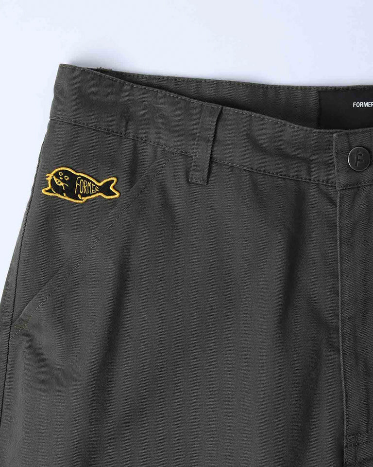 Close-up of front pocket with yellow Former fish logo embroidery on dark olive fabric