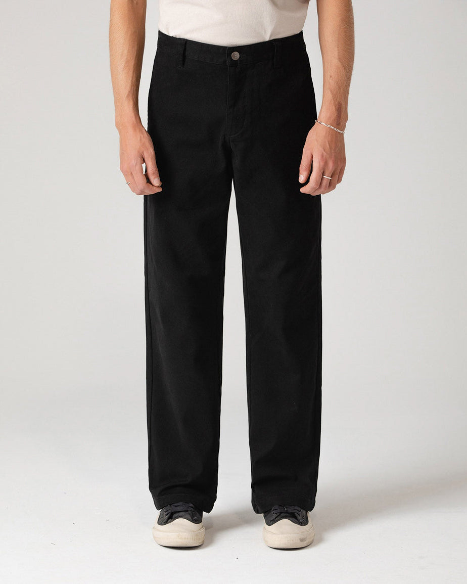 Black straight-leg pants styled with white sneakers, shown from the front.