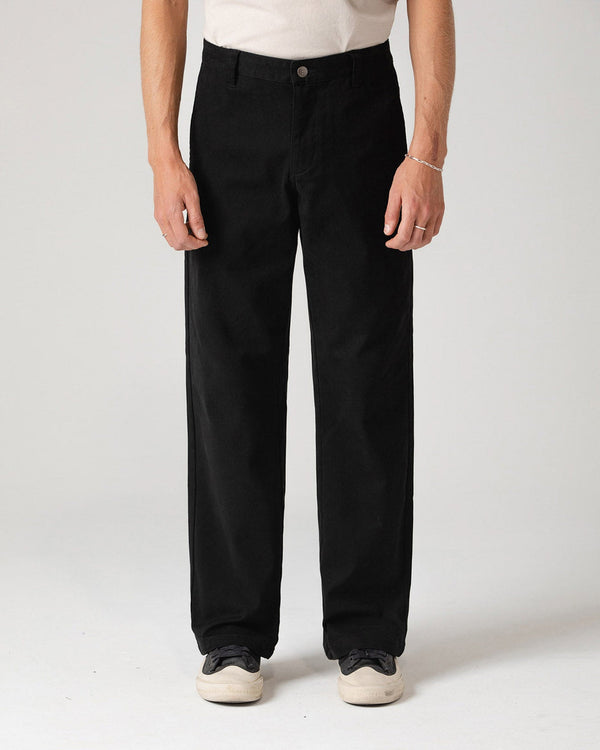 Black straight-leg pants styled with white sneakers, shown from the front.