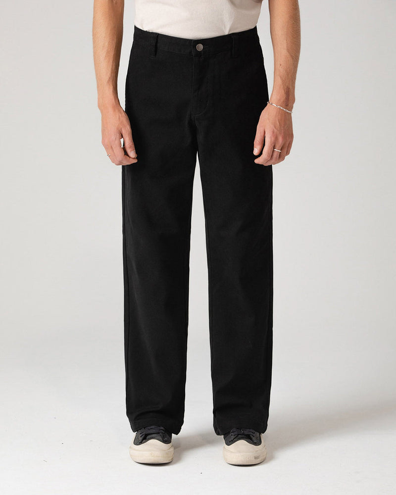 Black straight-leg pants styled with white sneakers, shown from the front.