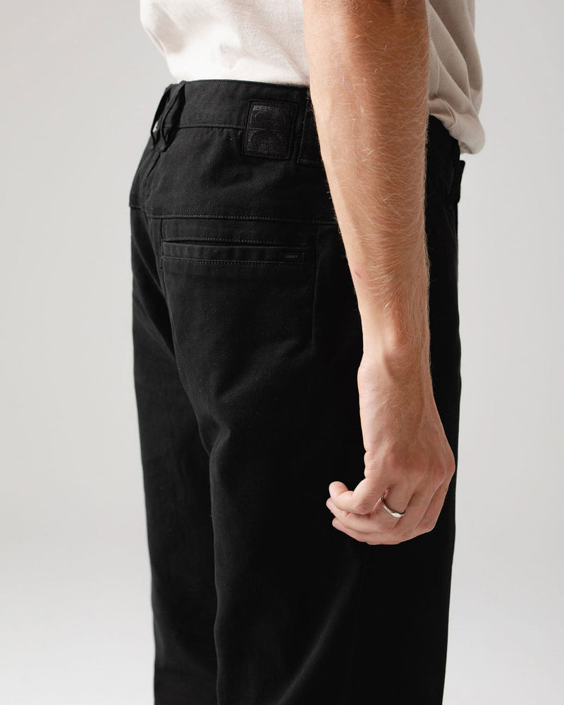 Close-up of back waistband and pocket detailing on black pants.