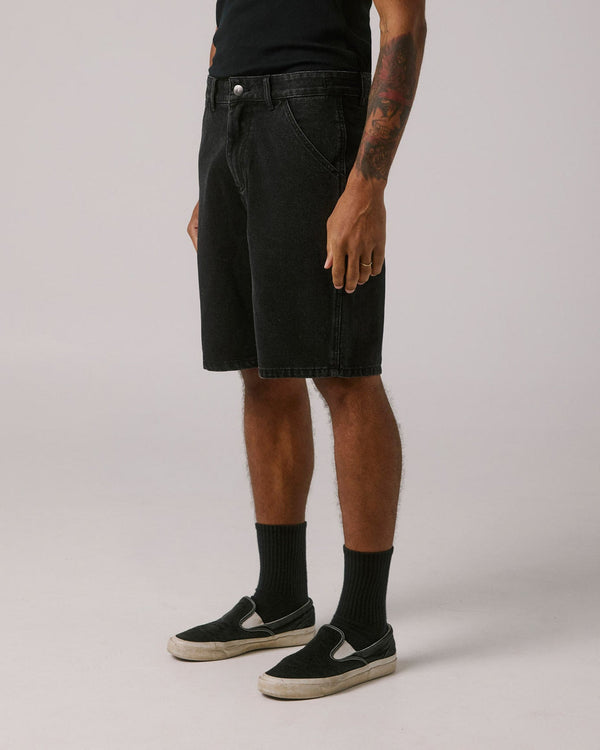 Model wearing black denim shorts, angled side view
