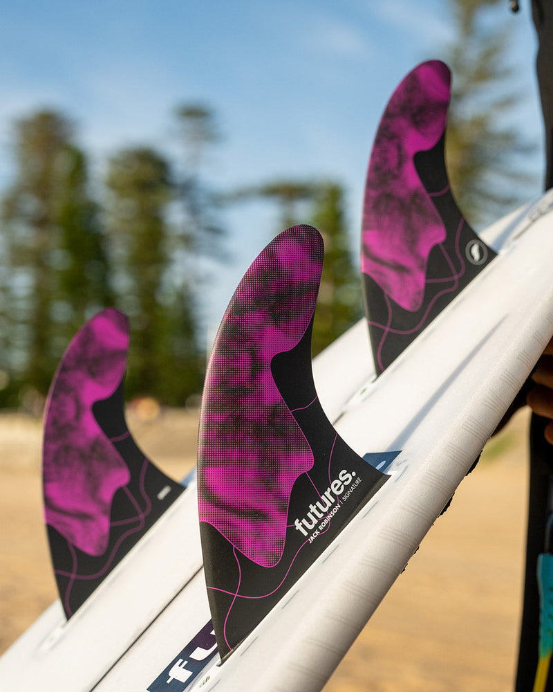 Futures Jack Robinson fins installed on a white board, featuring vibrant purple detail and pro-level construction.