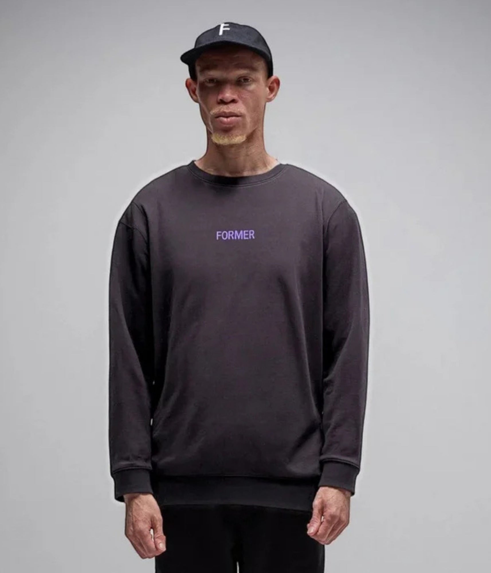 Person wearing a dark long-sleeve shirt with 'FORMER' text on a gray background