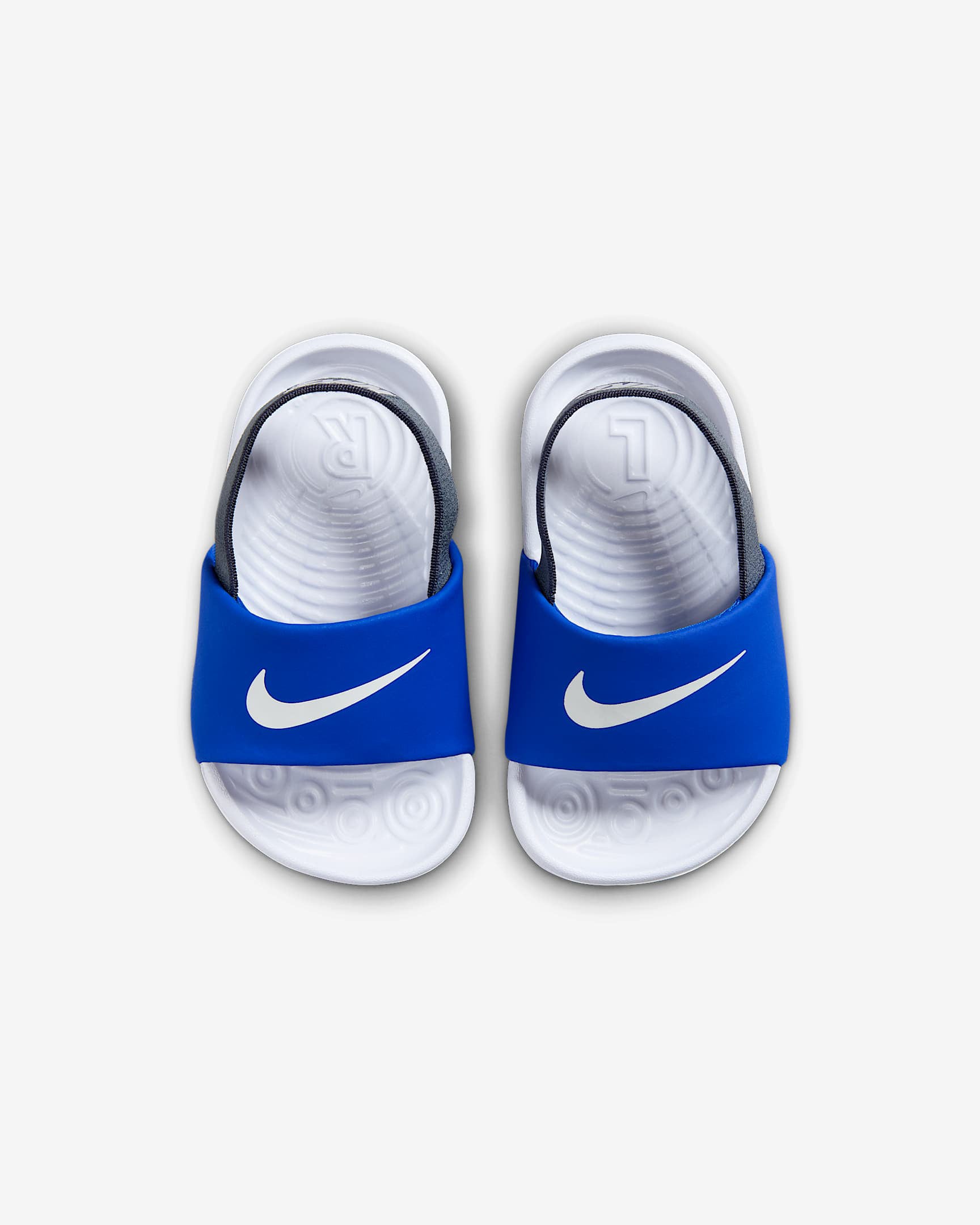Top view of blue Nike kids' slides with white Swoosh logos and contoured white footbeds.