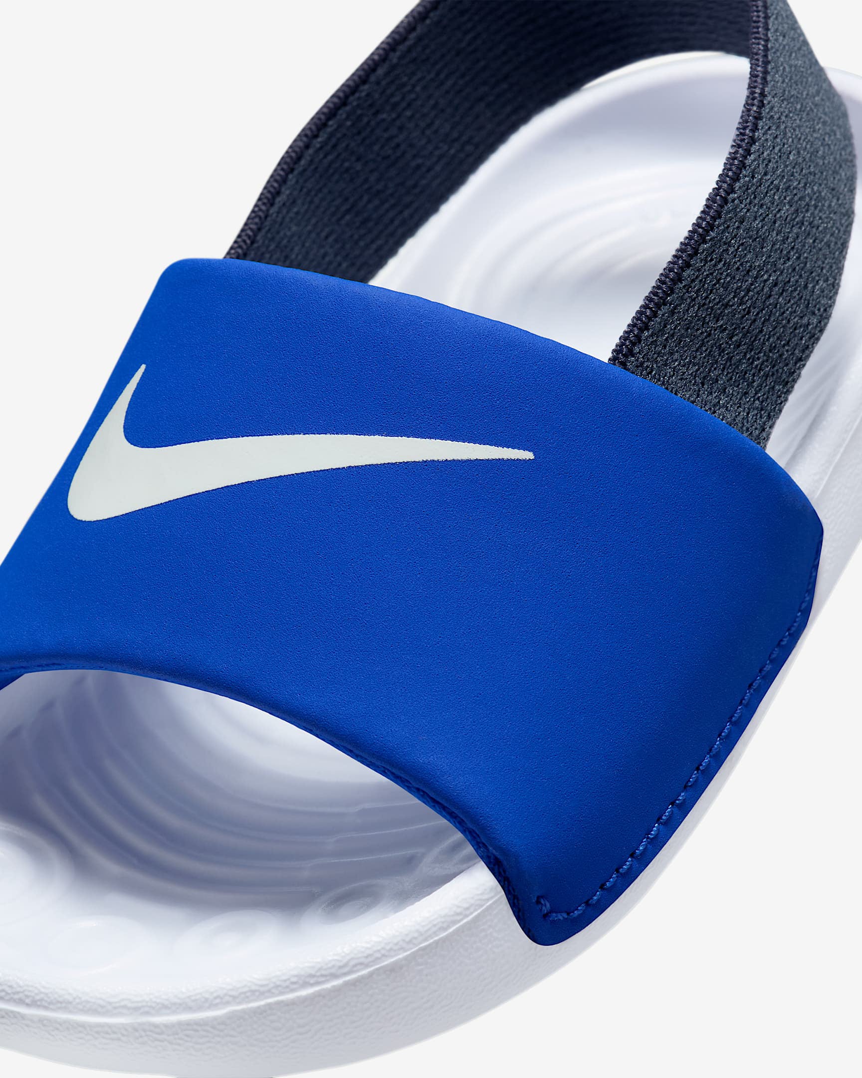 Close-up of blue Nike kids' slide showcasing white Swoosh logo and textured white footbed.