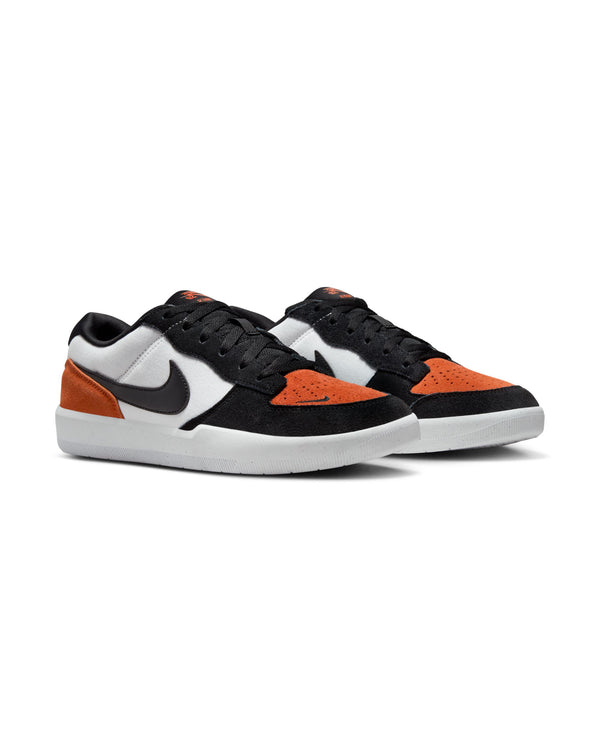 A pair of low-top sneakers with black, white, and orange suede panels, a black Nike swoosh, and white rubber soles, shown at an angle.