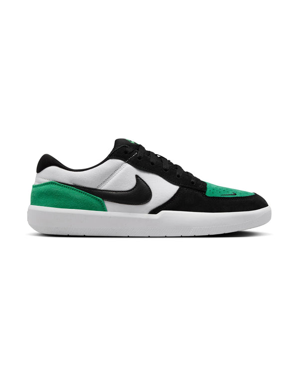 A side view of low-top sneakers with a black, white, and green color scheme, featuring a black Nike swoosh and white sole.