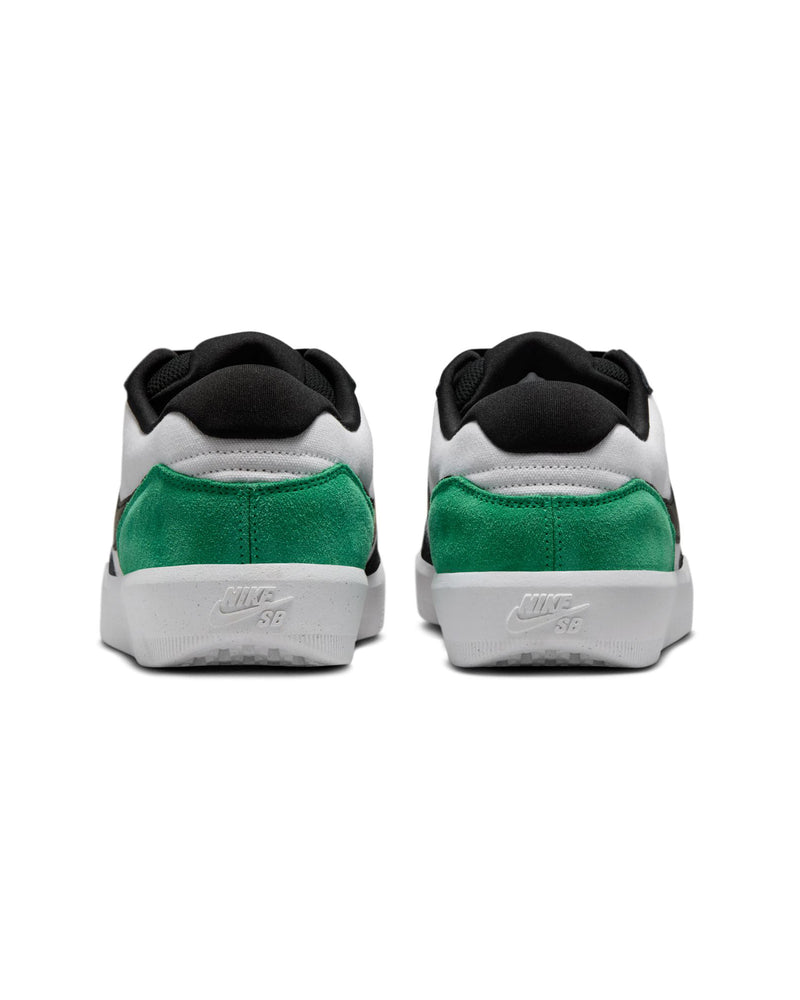 Rear view of low-top sneakers featuring green suede heels, black collars, white panels, and "Nike SB" branding on white rubber soles.