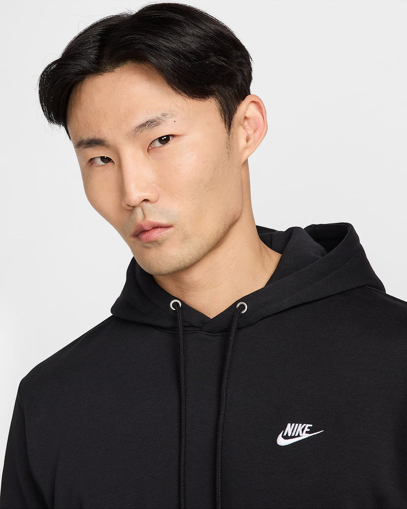 Close-up of a man wearing a black Nike hoodie showing the chest logo and hood drawstrings.
