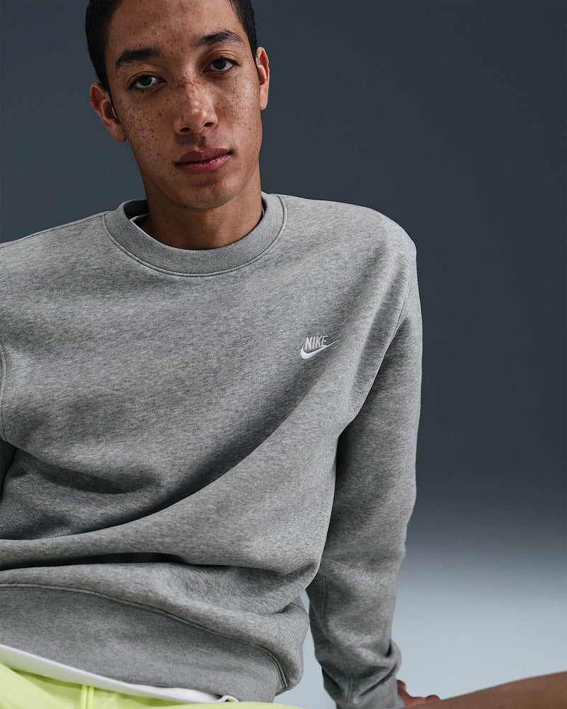 Close-up of grey Nike sweatshirt with white embroidered swoosh logo on chest
