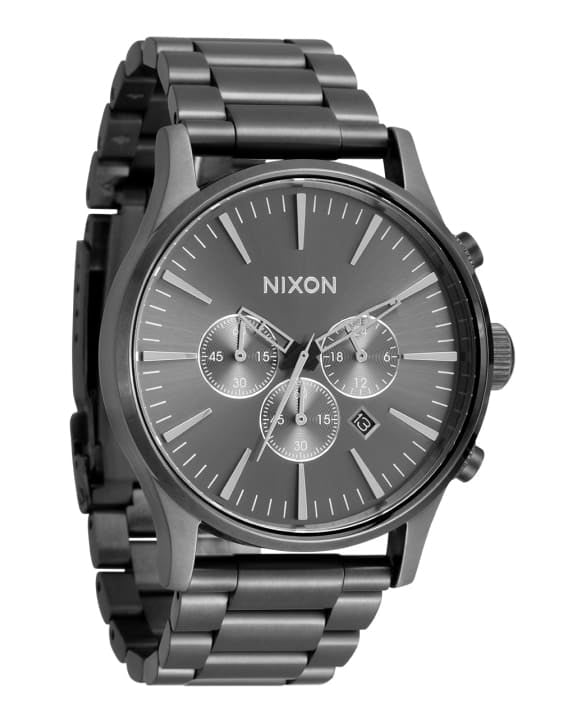 Angled view of a Nixon chronograph watch with a gray dial, minimalist markers, three sub-dials, and a polished black metal bracelet.