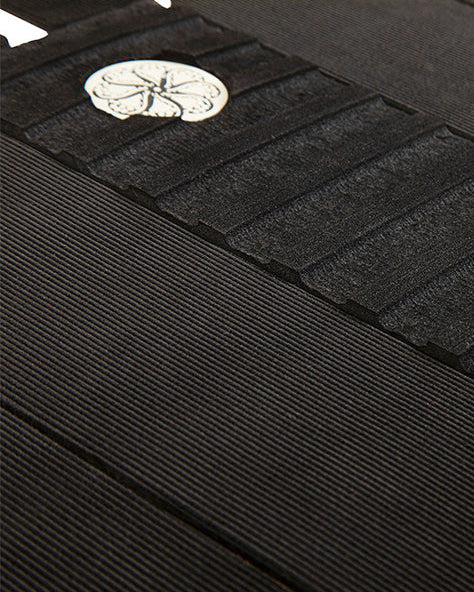Close-up of black grip pad showing grooved arch bar, ribbed panels, and circular logo detail.