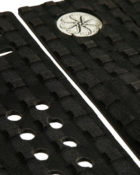 Close-up of woven texture and logo detail on black surfboard traction pad.