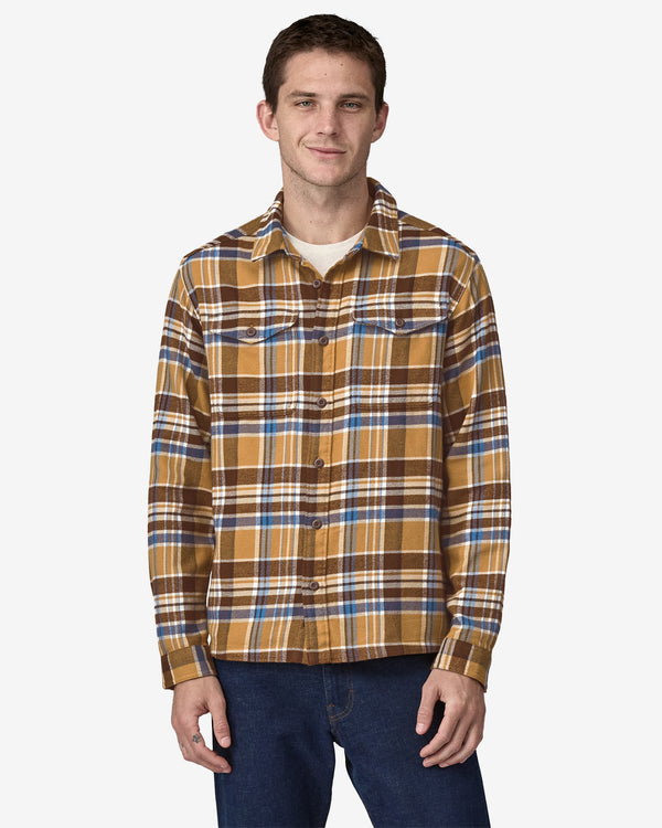 Man wearing a mustard, brown, and blue plaid flannel shirt with button closures and chest pockets, paired with jeans.