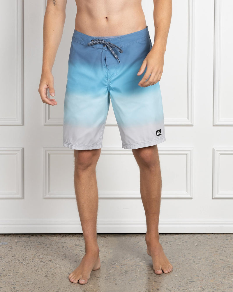 Front view of blue to grey ombre Quiksilver boardshorts with drawstring waist and logo patch.