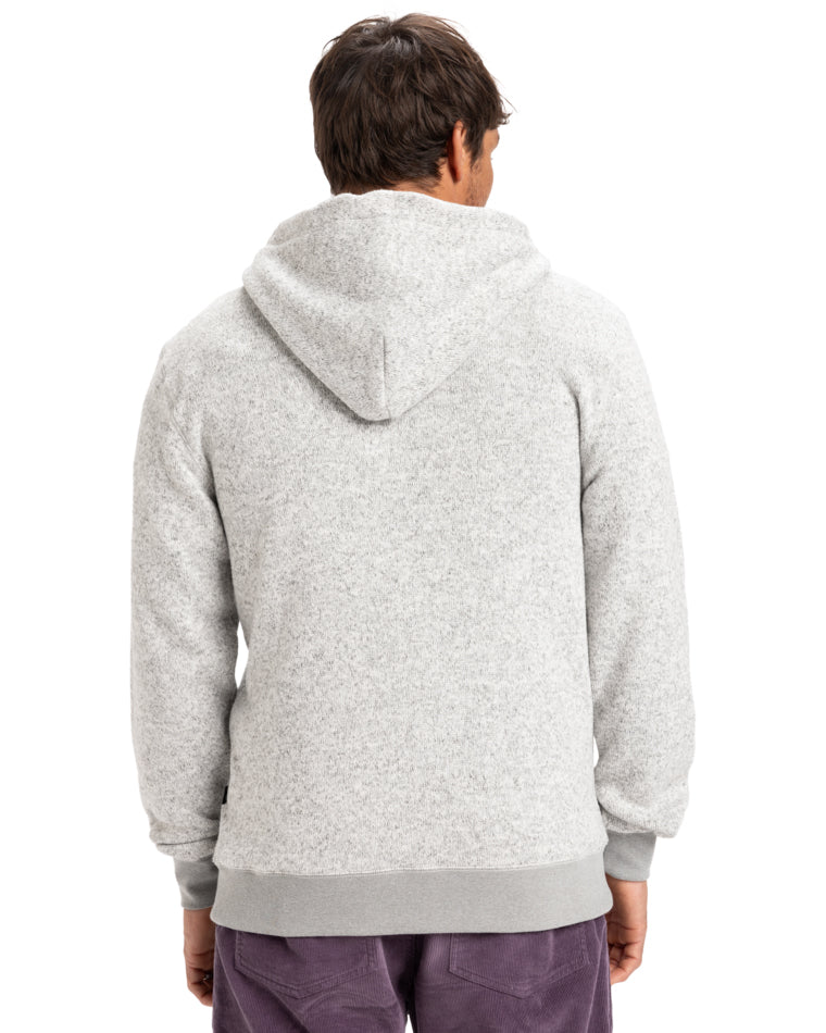 Man seen from the back wearing a light gray hoodie with a hood up and ribbed cuffs, paired with purple pants