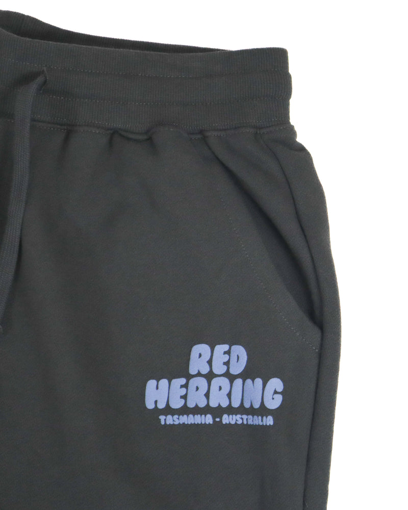 Close-up of Red Herring Tasmania Australia logo on front pocket of black jogger pants.