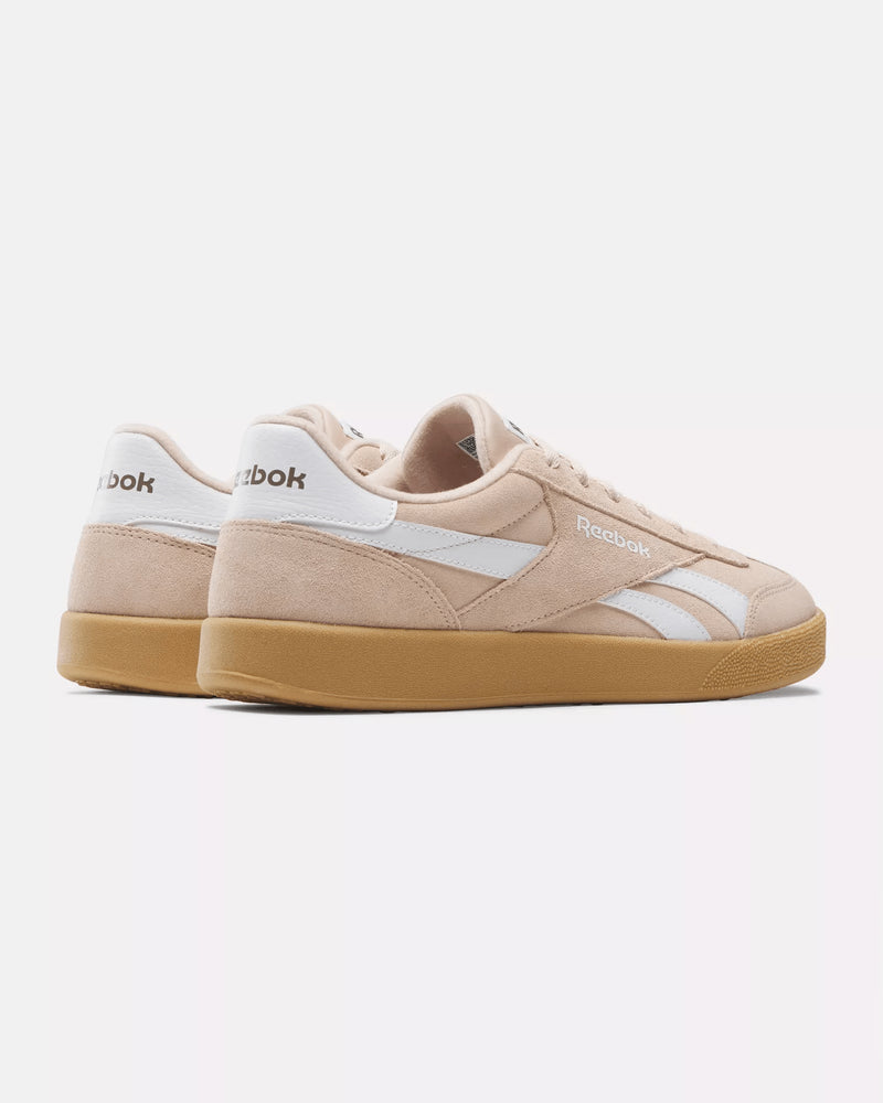 Rear angled view of beige Reebok sneakers featuring white logo accents, gum outsole, and a retro-inspired design.