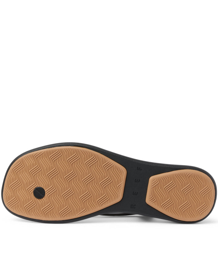 Black thong sandal with tan sole, bottom view showing tread pattern.