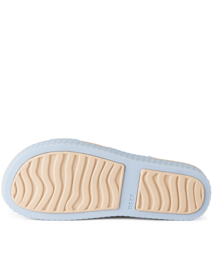 Outsole view of Reef sandals with textured beige tread and flexible light blue base