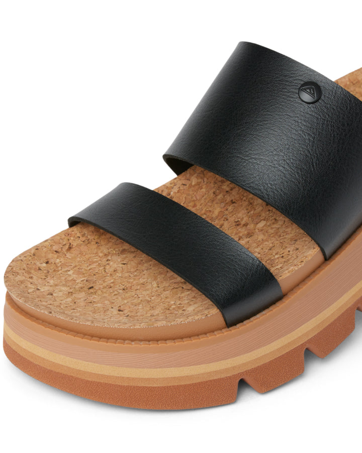 Close-up of black sandal with wide leather-look straps and layered platform base