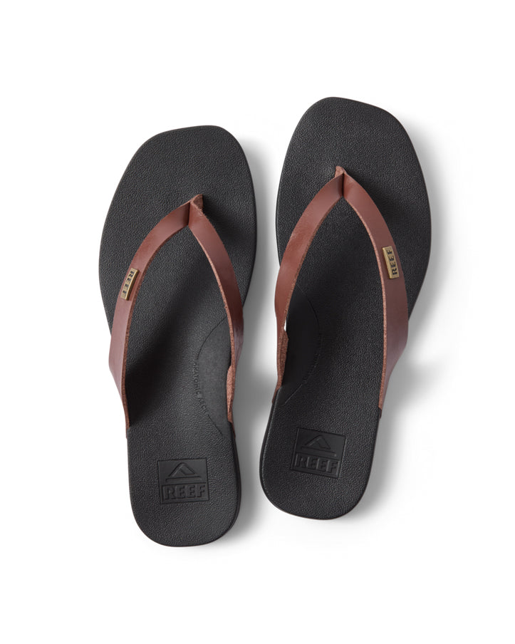 Brown strap thongs with black sole and Reef logo on footbed and strap
