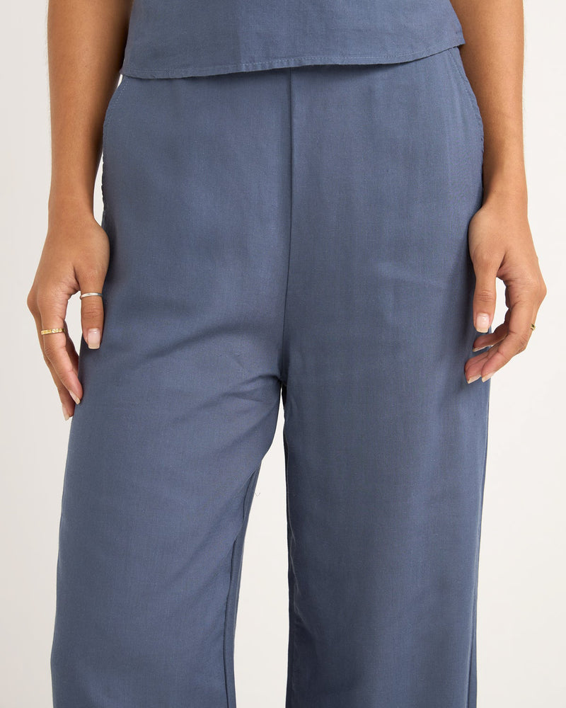 Close-up of high-waisted, wide-leg blue pants with a smooth finish and relaxed fit, paired with a matching top.