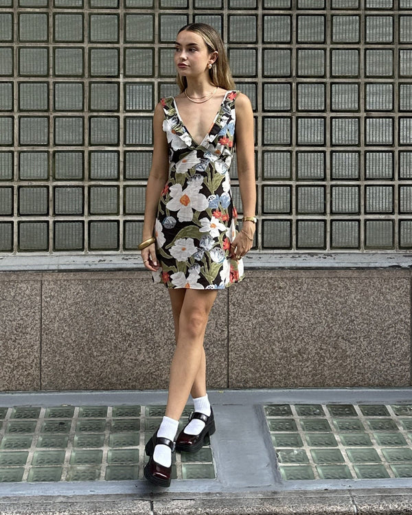 A model wearing a floral V-neck dress with ruffle details, paired with white socks and black platform shoes.