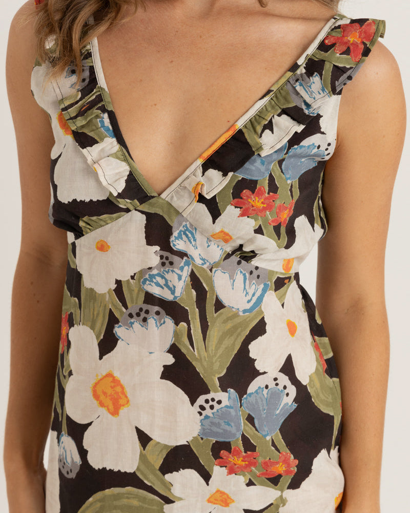 A close-up of a floral V-neck dress featuring ruffled straps and a mix of white, red, and blue flowers on a black background.