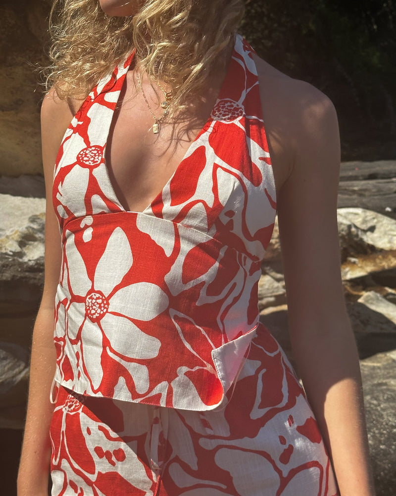 Close-up of a floral halter top in vibrant red and white, featuring a deep V-neckline and an elegant fitted design.