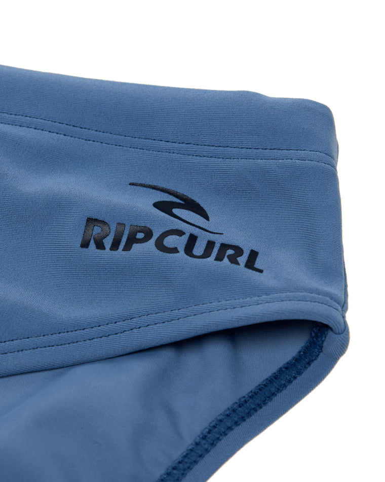 Close-up of Rip Curl logo on blue swim briefs with detailed stitching.